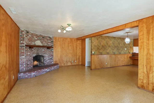 a view of an empty room with a fireplace and a window