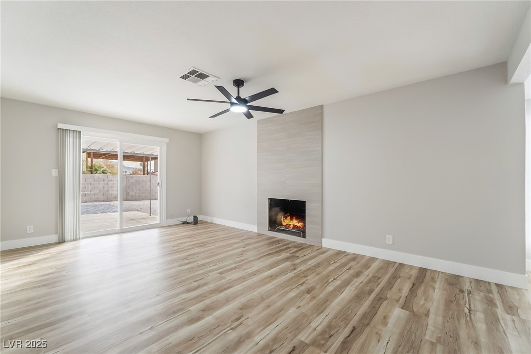 652 Red Lake Way Las Vegas, NV 89110 - Photo 13 of 66 Unfurnished living room with a large fireplace, light wood finished floors, and ceiling fan