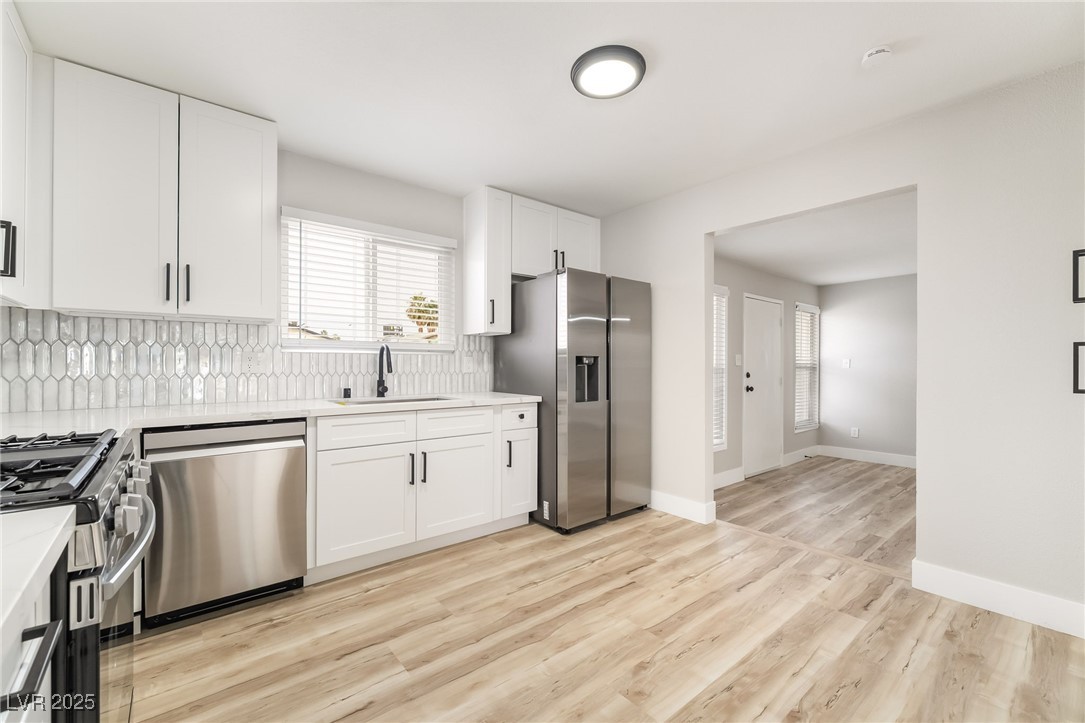 652 Red Lake Way Las Vegas, NV 89110 - Photo 10 of 66 Kitchen featuring stainless steel appliances, white cabinetry, decorative backsplash, and healthy amount of natural light