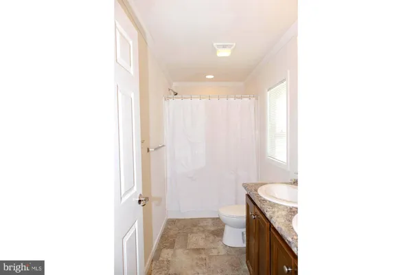 a bathroom with a granite countertop sink a toilet and shower