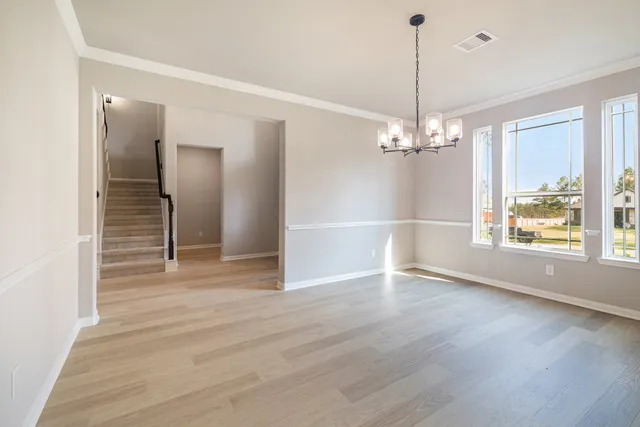 a view of a livingroom with wooden floor staircase and a kitchen space