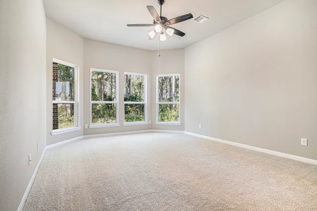 an empty room with windows and fan
