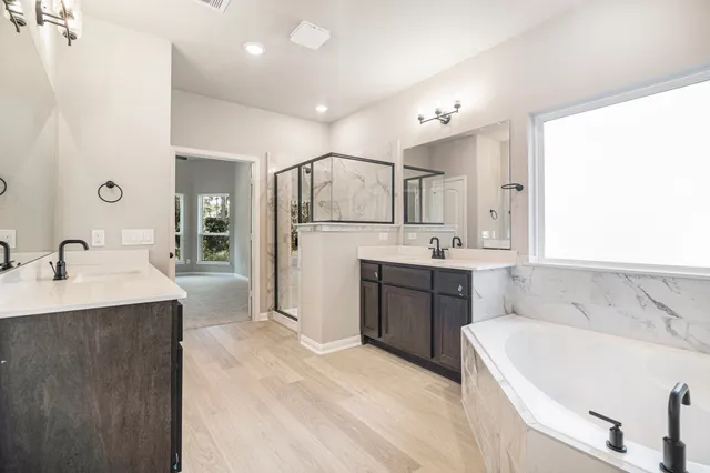 a spacious bathroom with a tub sink and mirror