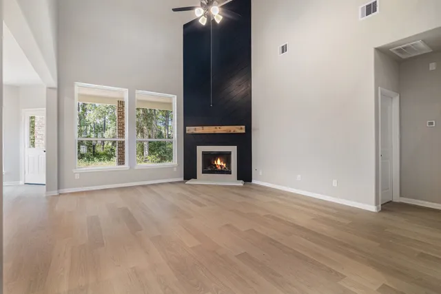 an empty room with wooden floor fireplace and windows