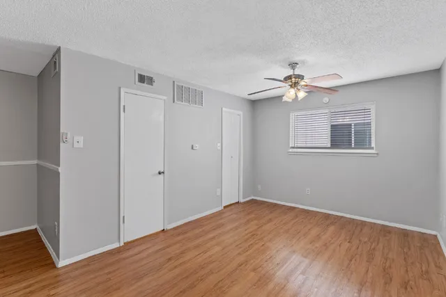 a view of a big room with wooden floor and a ceiling fan