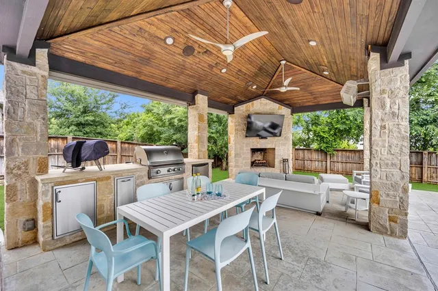 a view of a patio with a table and chairs under an umbrella with a barbeque