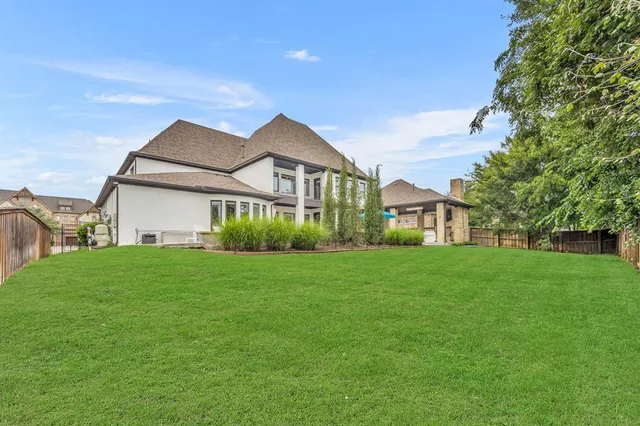 a view of a big house with a big yard plants and large trees
