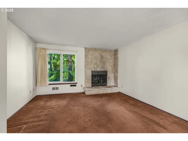 a view of an empty room with a fireplace and a window