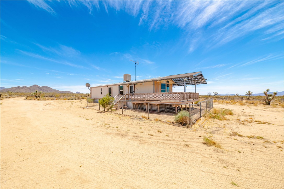 16435 South Wyatt Earp Road Yucca, AZ 86438 - Photo 54 of 57 Single-story residence featuring an elevated deck with a partial shade structure, wood-tone railing, and a fenced perimeter