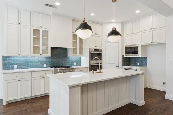 a kitchen with kitchen island stainless steel appliances a sink a stove and a wooden floors