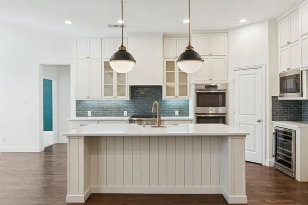 a kitchen with stainless steel appliances granite countertop a sink a refrigerator a stove a kitchen island with wooden floor and cabinets