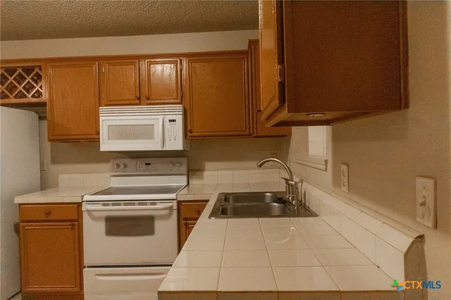 a kitchen with granite countertop a stove a sink and a microwave