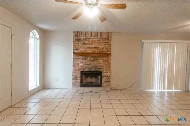 an empty room with windows and fireplace