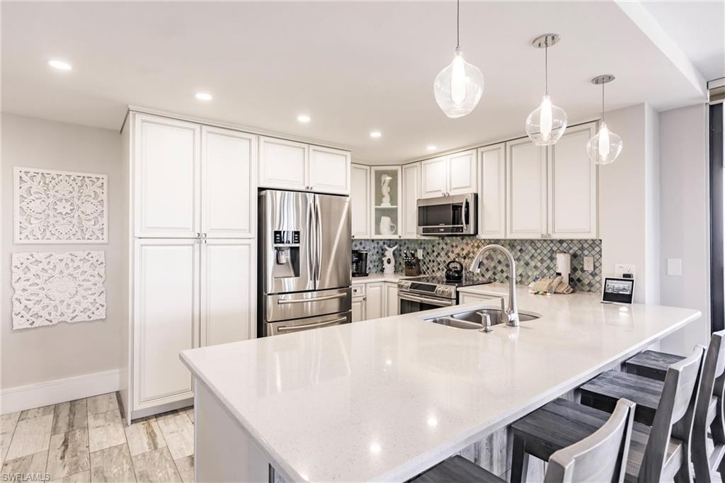 17170 Harbour Point Drive, Unit 437 Fort Myers, FL 33908 - Photo 7 of 41 Kitchen with sink, a kitchen breakfast bar, kitchen peninsula, decorative light fixtures, and appliances with stainless steel finishes
