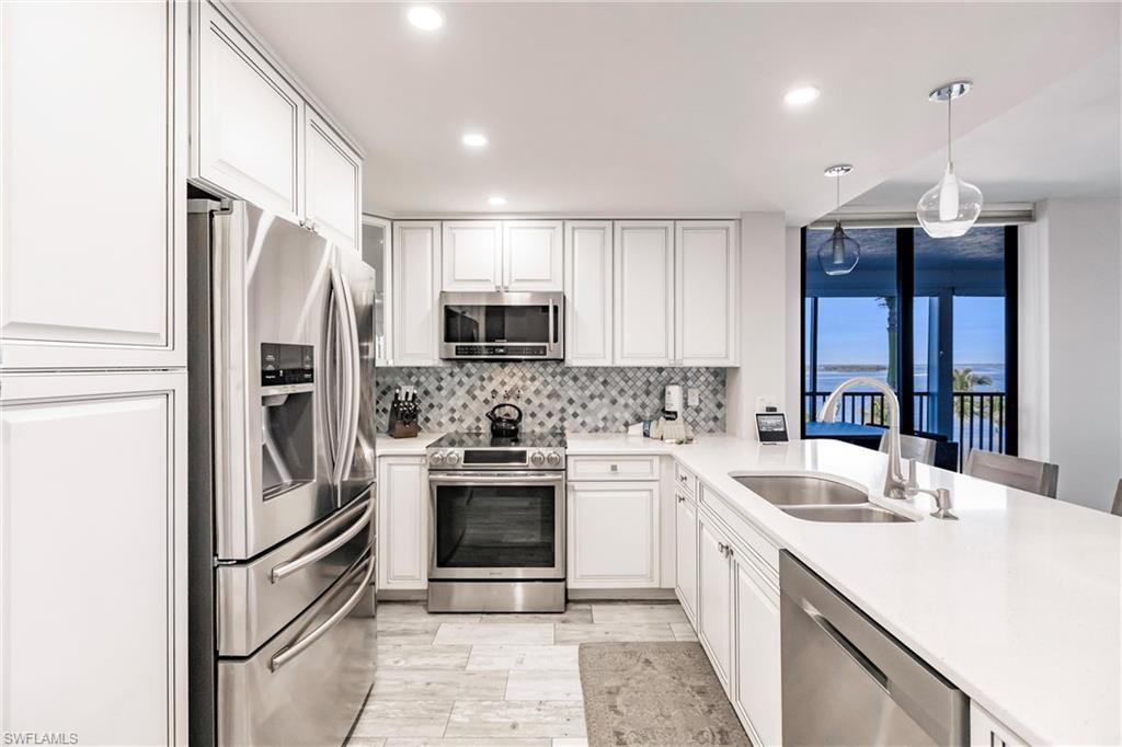 17170 Harbour Point Drive, Unit 437 Fort Myers, FL 33908 - Photo 9 of 41 Kitchen with sink, hanging light fixtures, tasteful backsplash, white cabinets, and appliances with stainless steel finishes