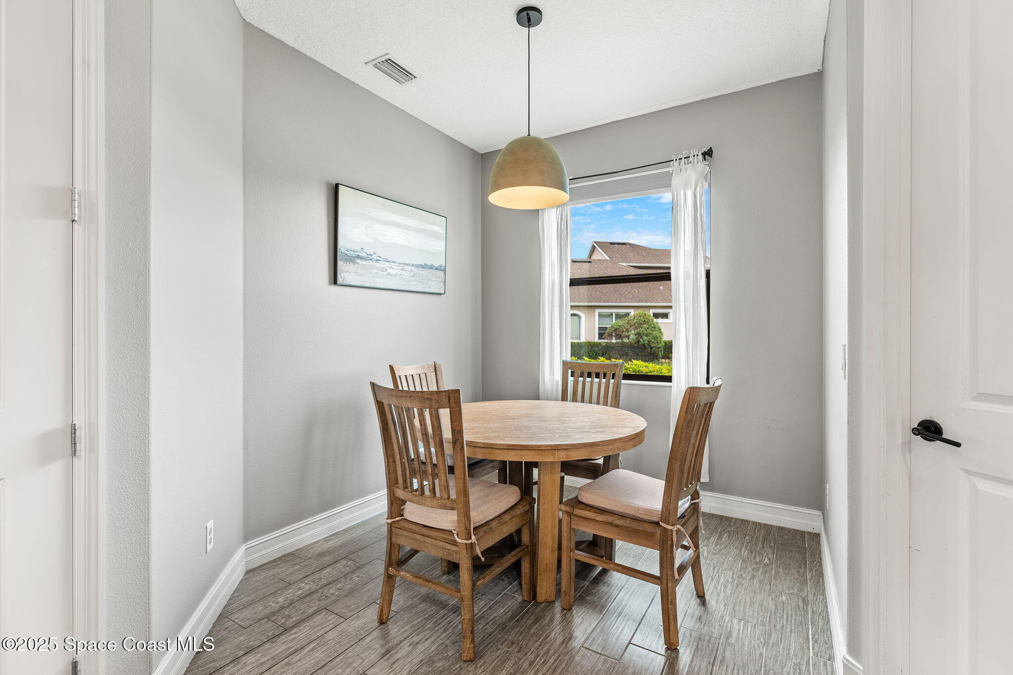8545 Stalwart Circle Melbourne, FL 32940 - Photo 19 of 51 a dining room with wooden floor a chandelier a wooden table and chairs