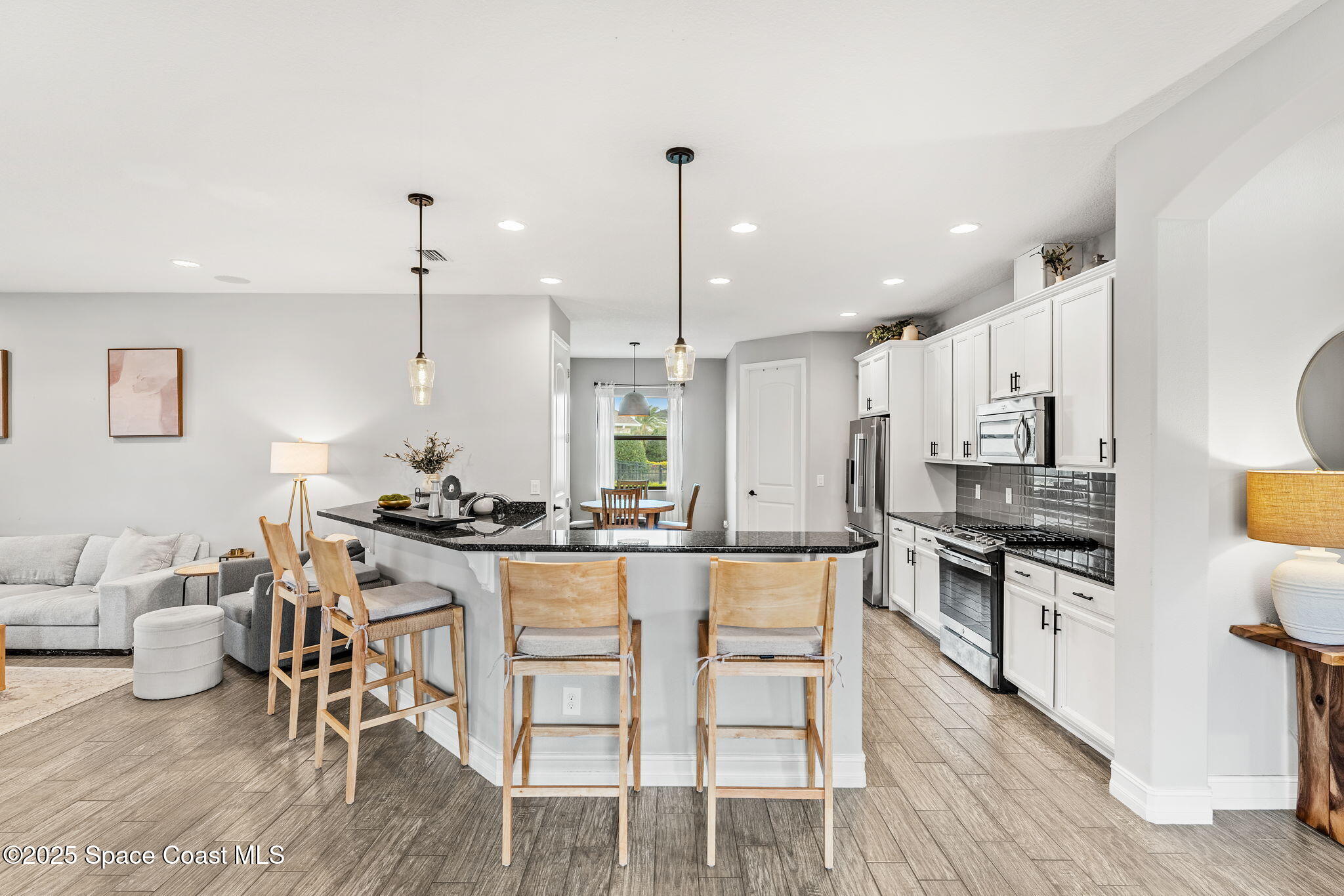 8545 Stalwart Circle Melbourne, FL 32940 - Photo 5 of 51 a kitchen with stainless steel appliances kitchen island granite countertop a stove a sink a dining table and chairs with wooden floor