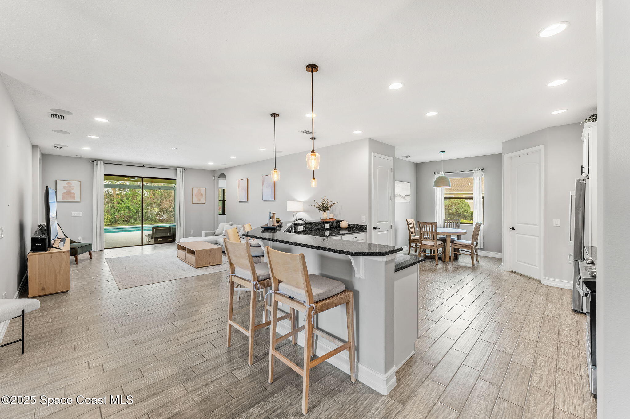 8545 Stalwart Circle Melbourne, FL 32940 - Photo 8 of 51 a dining hall with stainless steel appliances granite countertop a stove a sink a dining table and chairs with wooden floor