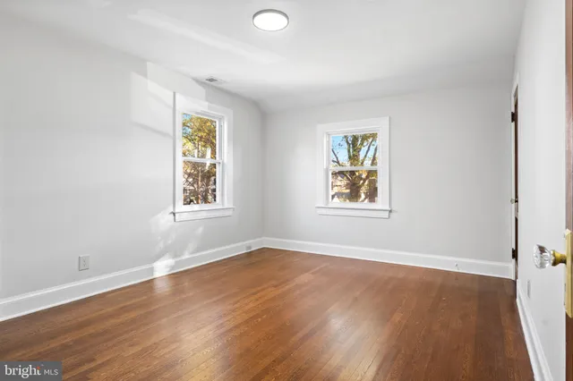 a view of an empty room with wooden floor and window