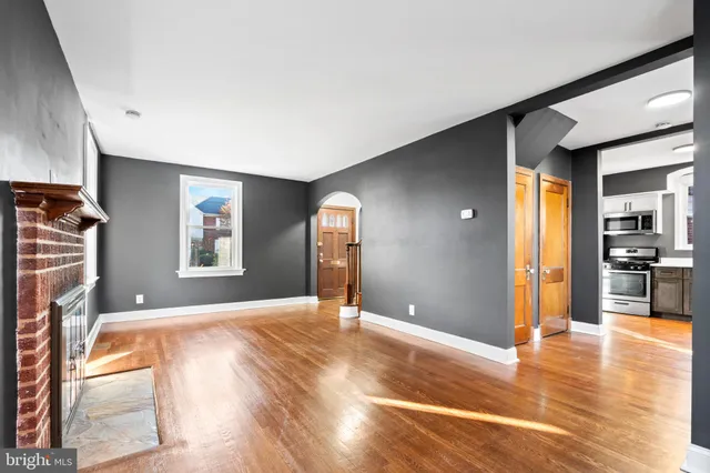 a view of an empty room with window and wooden floor