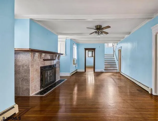 a view of a livingroom with a fireplace a ceiling fan and windows