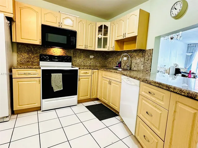 a kitchen with granite countertop a stove a sink and a microwave