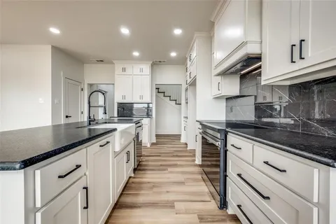 an open kitchen with kitchen island a sink appliances wooden floor and a large window