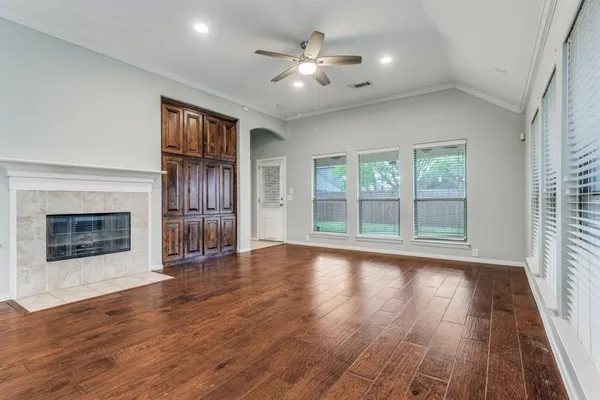 wooden floor fireplace and windows in an empty room