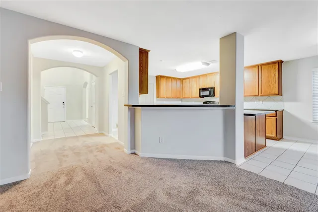 a view of an empty room with window and chandelier fan