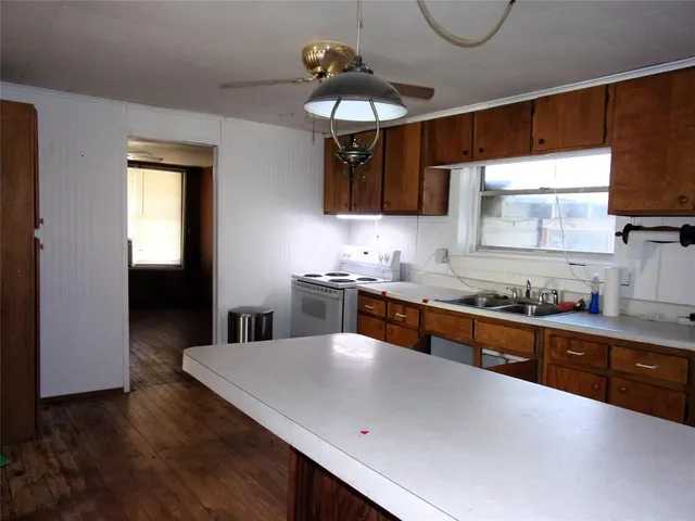 a kitchen with stainless steel appliances a sink a stove a refrigerator cabinets and a dining table