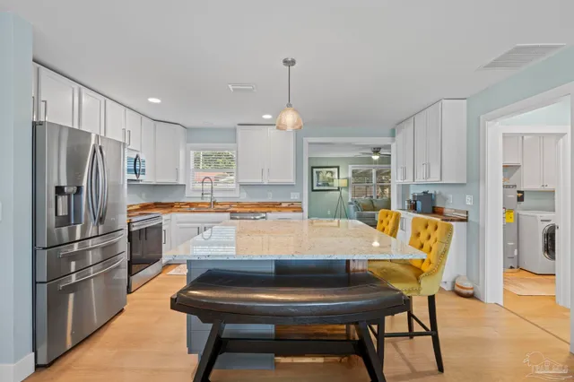 a kitchen with stainless steel appliances granite countertop a refrigerator a sink a stove and white cabinets