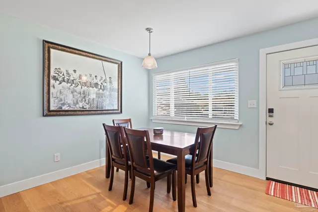a dining room with wooden floor a chandelier a wooden table and chairs