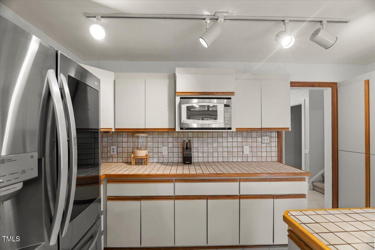 6117 Dodsworth Drive Raleigh, NC 27612 - Photo 15 of 54 a kitchen with kitchen island a counter top space a refrigerator and cabinets