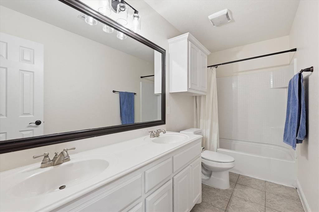 430 Ridgecrest Place Sanger, TX 76266 - Photo 23 of 40 Bathroom featuring a dual vanity with white cabinetry, a large framed mirror, brushed nickel faucets, a built-in bathtub with shower, and tile flooring