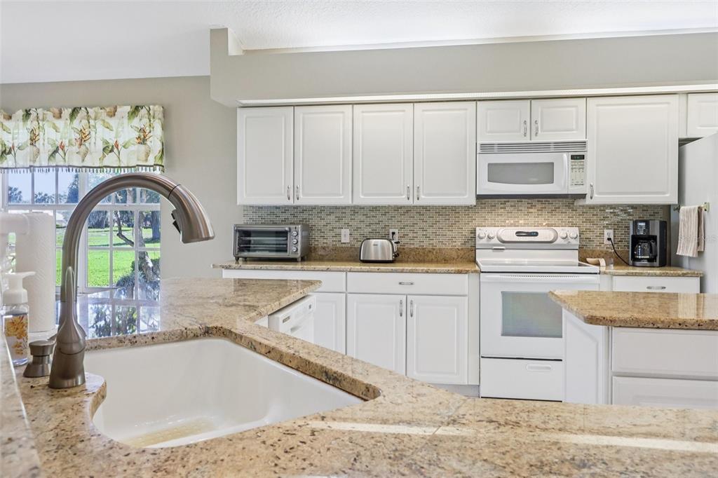 587 Juniper Way Tavares, FL 32778 - Photo 19 of 56 a kitchen with stainless steel appliances granite countertop a sink a stove cabinets and a counter top space