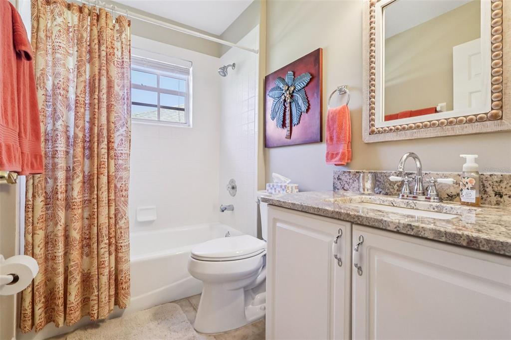 587 Juniper Way Tavares, FL 32778 - Photo 31 of 56 a bathroom with a granite countertop sink a toilet and a shower curtain