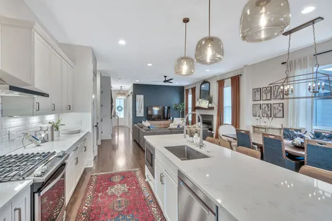 a large kitchen with lots of counter space a sink appliances and living room view