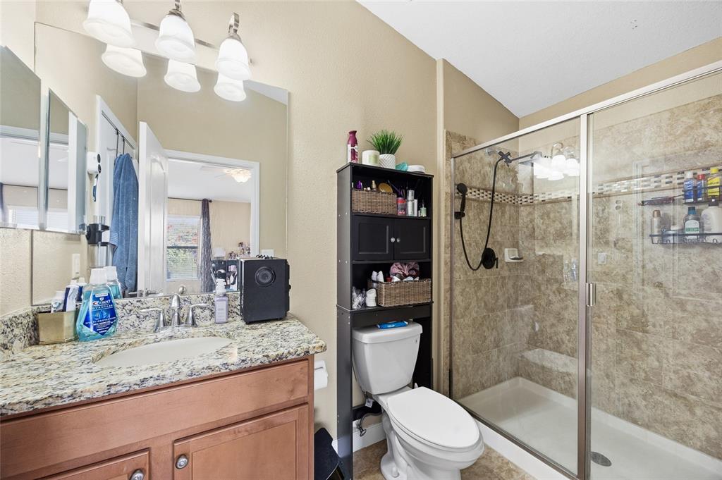 10019 Newminster Loop Ruskin, FL 33573 - Photo 18 of 34 a bathroom with a granite countertop sink a toilet a mirror a vanity and shower