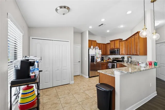 a kitchen with stainless steel appliances kitchen island granite countertop a refrigerator and a sink