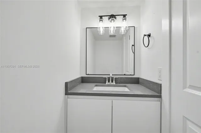 a bathroom with a granite countertop sink and a mirror