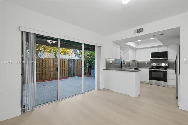 a kitchen with stainless steel appliances kitchen island granite countertop a refrigerator and white cabinets