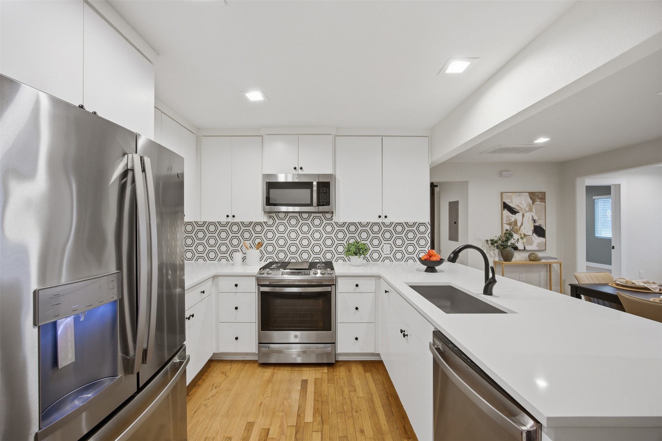 5116 Heflin Lane, Unit 1 Austin, TX 78721 - Photo 10 of 35 A sleek, contemporary kitchen presents a captivating geometric backsplash and gleaming hardwood flooring.