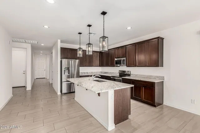 a kitchen with stainless steel appliances a stove a sink a refrigerator and chairs