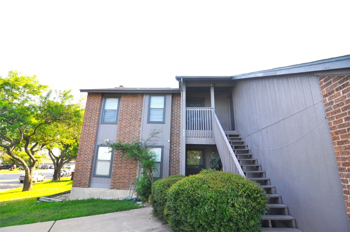 400 Rawhide Loop, Unit 406 Round Rock, TX 78681 - Photo 1 of 1 a view of a house with brick walls and a yard with plants and a large tree