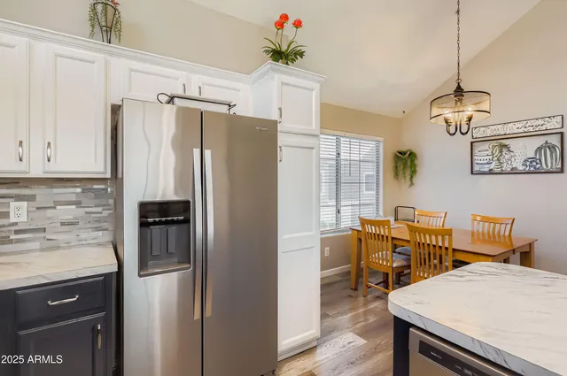 a kitchen with stainless steel appliances wooden floor and white cabinets