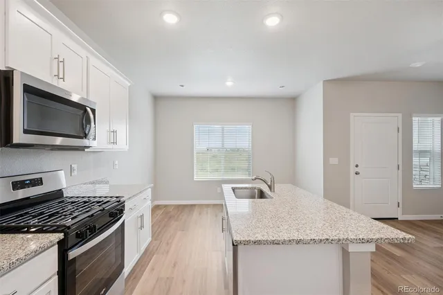 a kitchen with granite countertop stainless steel appliances a sink cabinets and a stove top oven