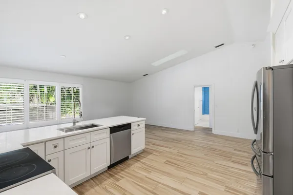 a kitchen with stainless steel appliances granite countertop a sink cabinets and wooden floor