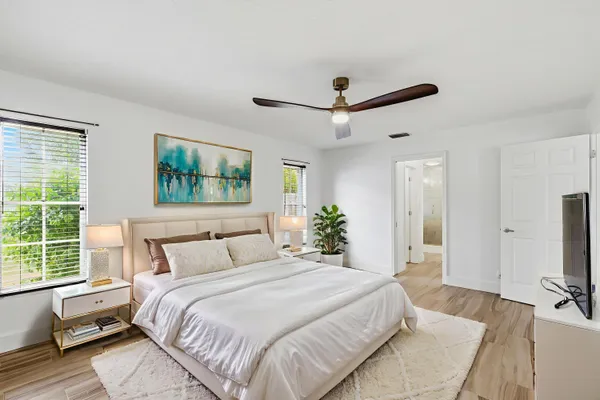 a bedroom with a large bed a flat tv screen and a large window with the garden view