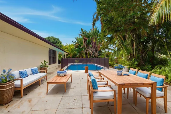 a view of a patio with a dining table and chairs under an umbrella with potted plants