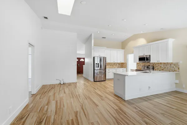a room with stainless steel appliances kitchen island wooden floors and white walls
